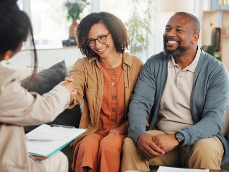 Financial advisor shaking hands with a mature couple at home after discussing life insurance and estate planning.
