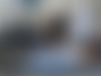 A Personal Trainer assists woman in stretching on a gym mat at Impact One Fitness in Woodland Hills, CA. Background includes dumbbells, kettlebells, and other exercise equipment.