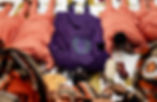 Five people lie face down on a patterned floor; four in peach Yoruba traditional outfits and one in purple. Hands hold a feather and money in the foreground. They are prostrating to the Bride's family to ask for her hand in marriage in accordance to Yoruba tradition.