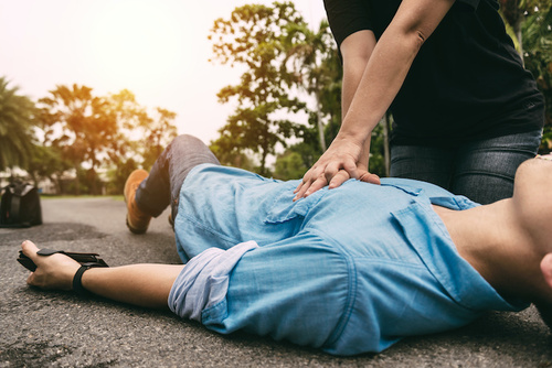Person receiving CPR on pavement; someone administering first aid training. Microfirm Training.