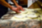 Mani che tirano la pasta della pizza