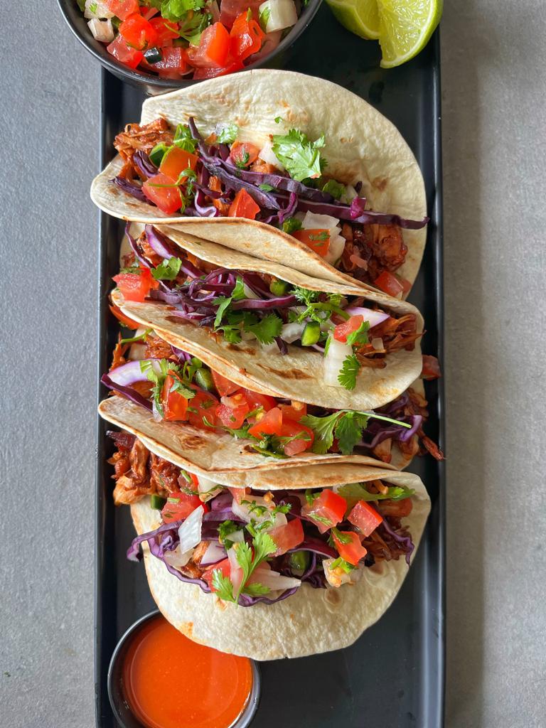 Smoky BBQ jackfruit tacos with red cabbage, pico de gallo, avocado, and lime