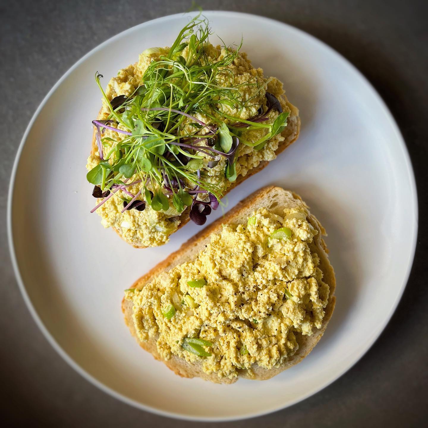 Creamy vegan tofu egg salad served on bread with fresh greens