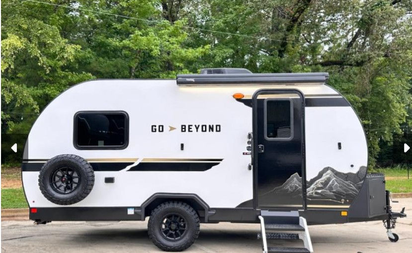 White Go Beyond camper trailer parked near green trees.