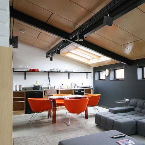 Internal photograph showing dining area beneath roof lights and a plywood vaulted ceiling with track lighting