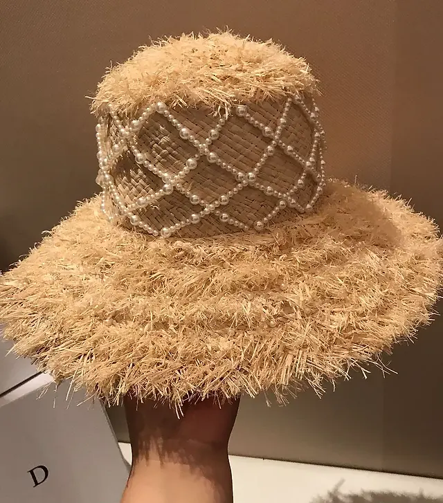 Sophisticated Summer Style: Pearl Elegance Raffia Straw Hat features hand-stitched pearls for a touch of luxury. Crafted from natural raffia, this sun hat offers breathable comfort and effortless elegance for your summer adventures.