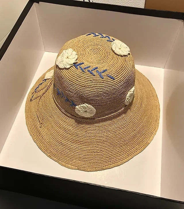 Blooming Summer Style: Floral Elegance Raffia Big Brim Hat features a beautiful floral design and wide brim for sun protection. Crafted from natural raffia, this hat adds a touch of elegance to your summer look.