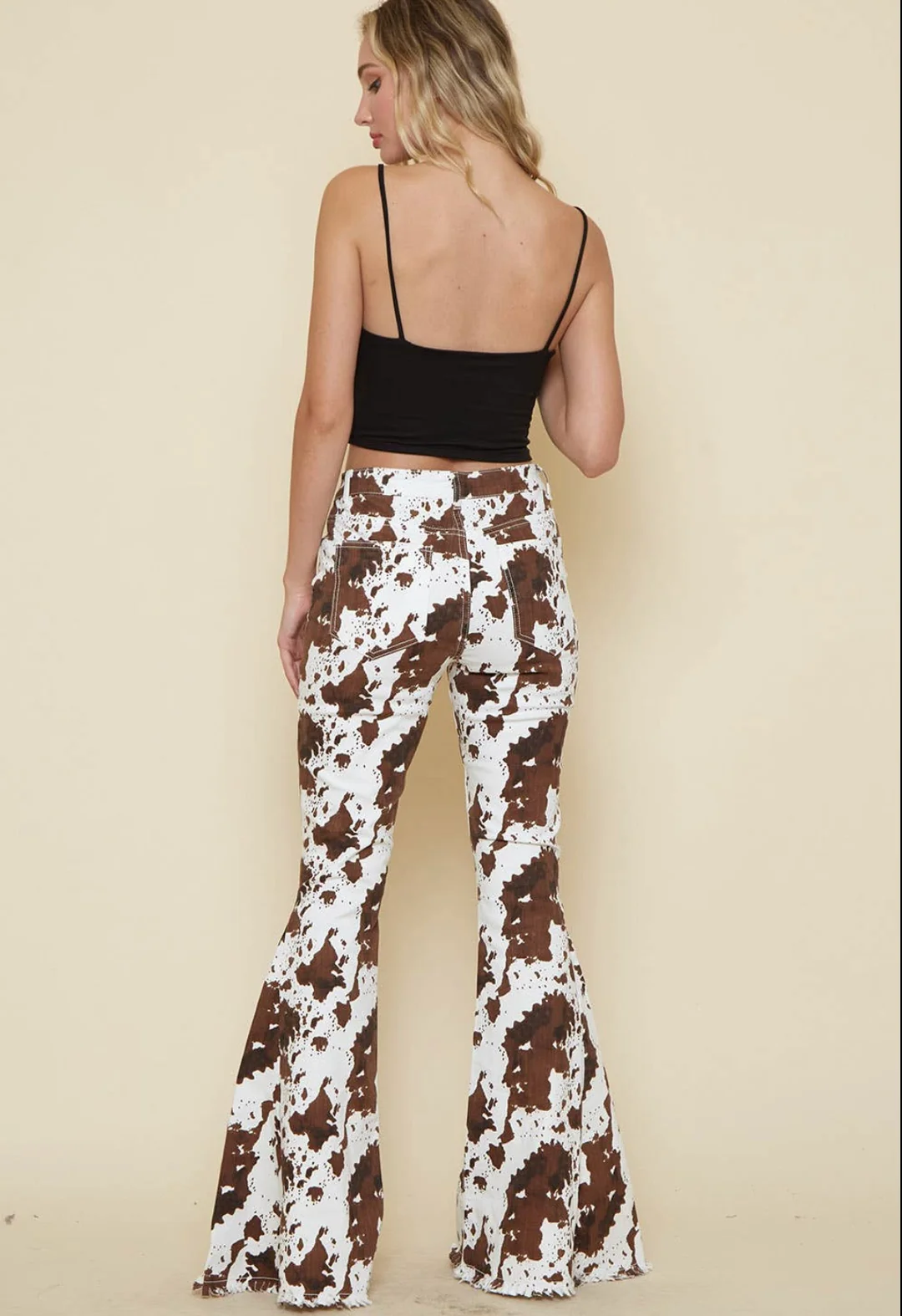 Model wearing white bell-bottom jeans with falling leaves print.