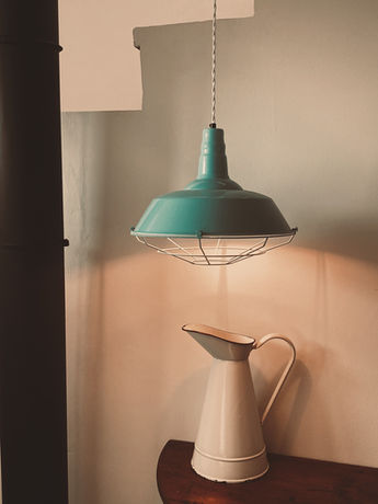 Jarra antigua de metal y lampara de techo en la zona de subida a la azotea de la Posada de la Luz