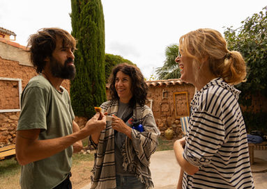 Tres amigos en una conversación animada muy sonrientes en la Posada de la Luz (Torralba de Ribota - Zaragoza),  coliving rural, coworking y talleres compartidos.