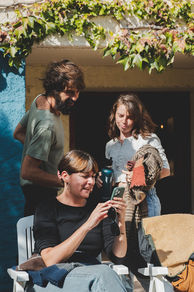 Tres personas mirando la pantalla de un móvil y conversando en la Posada de la Luz (Torralba de Ribota - Zaragoza),  coliving rural, coworking y talleres compartidos.