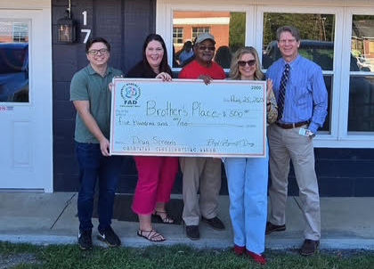 Brother's Place Directors and FAD Members holding a large check.