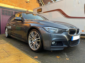 Grey BMW 3 Series parked beside a white caravan.