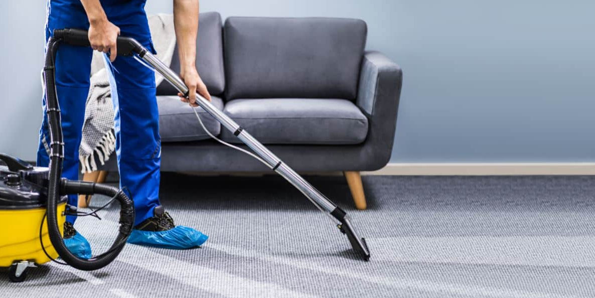 man-in-blue-overalls-wearing-shoe-covers-steam-cleaning-a-carpet..jpg