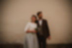 Ein glückliches Hochzeitspaar steht vor einer Wand.