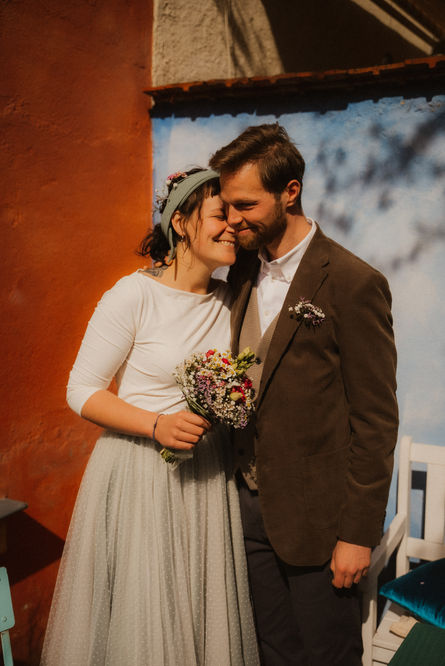 Ein Ehepaar steht Arm in Arm. Sie wirken leicht nervös aber glücklich.