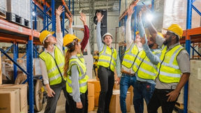 Group of workers in PPE high-five each other