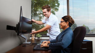 Ergonomist adjusts an office worker's monitor