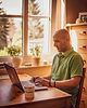 Mentaltrainer Ilias Moschos in der Profilansicht bei der Arbeit am Laptop vor einem hellen Fenster