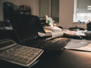 messy desk with a laptop and calculator