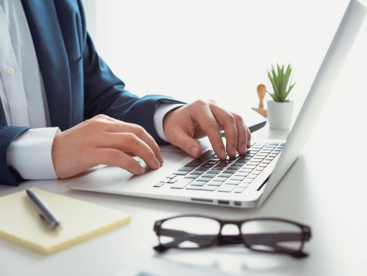 man's hands typing on a laptop