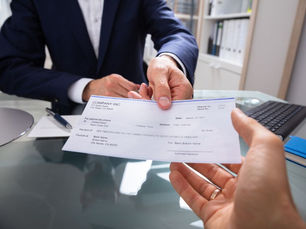 person handing a paycheck to another person