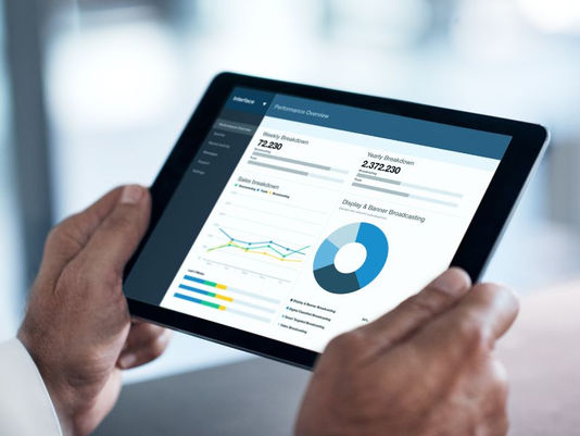 person's hands holding a tablet with number charts