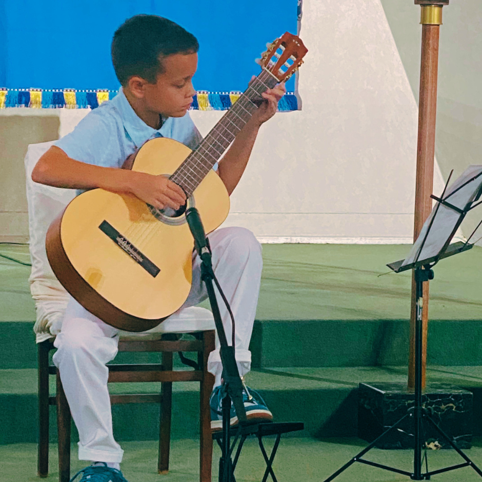 young boy student playing guitar at recital