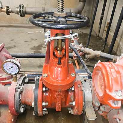 Red fire pump assembly with pressure gauge and piping during inspection by Alltron Systems