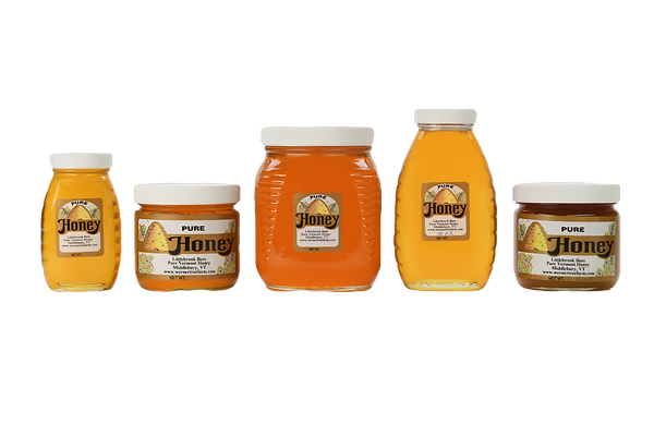 Five glass honey jars of different sizes with a white background.