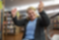 Woman with headphones on smiles while sitting in front of bookshelves