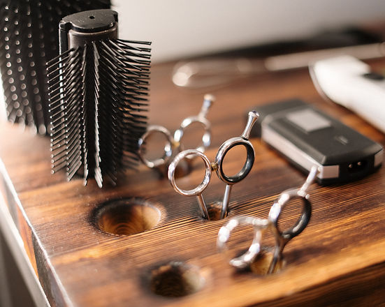 hairstylist tools on a table: sheers, round brush, clippers and a brush
