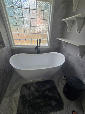 Modern bathroom with white freestanding tub under a window