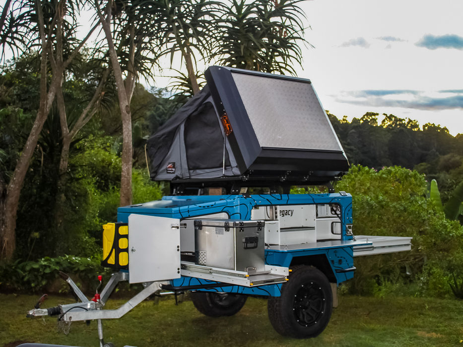 Legacy trailer fully opened, showing the kitchen, storage compartments, rooftop tent, and rear drawer system in use.