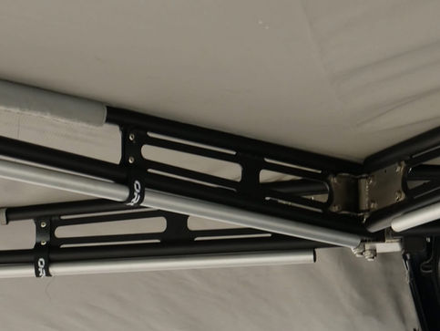 Close-up of the powder-coated aluminum awning arms showing the five drop-down legs securely strapped for transport.