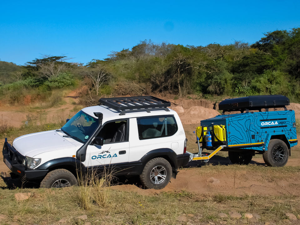 Trailer being towed over an uneven off-road course with alternating small hills, showing its suspension system in action and ability to maintain stability on rough terrain.