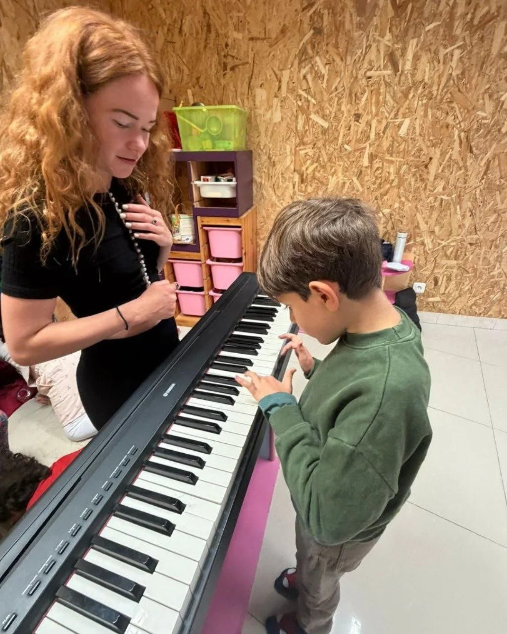 Une intervenante accompagne un enfant au piano