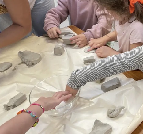 Des enfants façonnent des pièces d'argile autour d'une table
