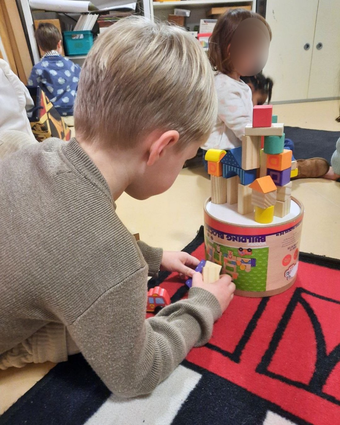 Un enfant construit une tour en blocs de bois colorés