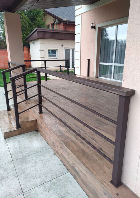 Металеве огородження з горизонтальним заповненням та дерев'яним поручнем на терасі приватного будинку.