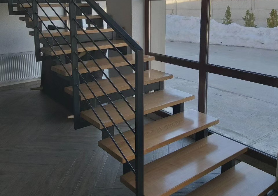 Сучасні інтер'єрні сходи на металевому каркасі зі сходинками з масиву ясеня та огородженням у стилі лофт.