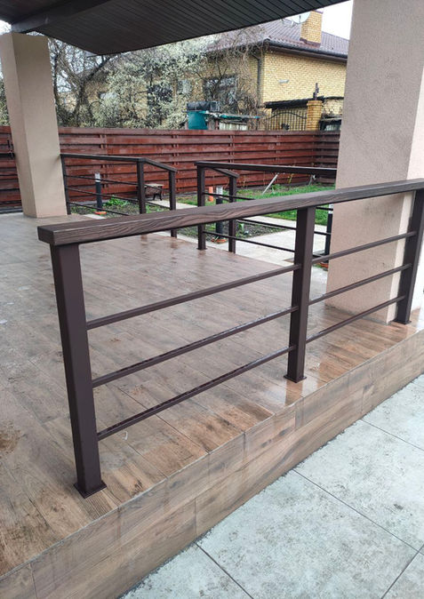 Металеве огородження з горизонтальним заповненням та дерев'яним поручнем на терасі приватного будинку.