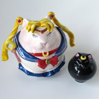 Una statuina di terracotta che raffigura Sailor Moon ma a forma di gatto