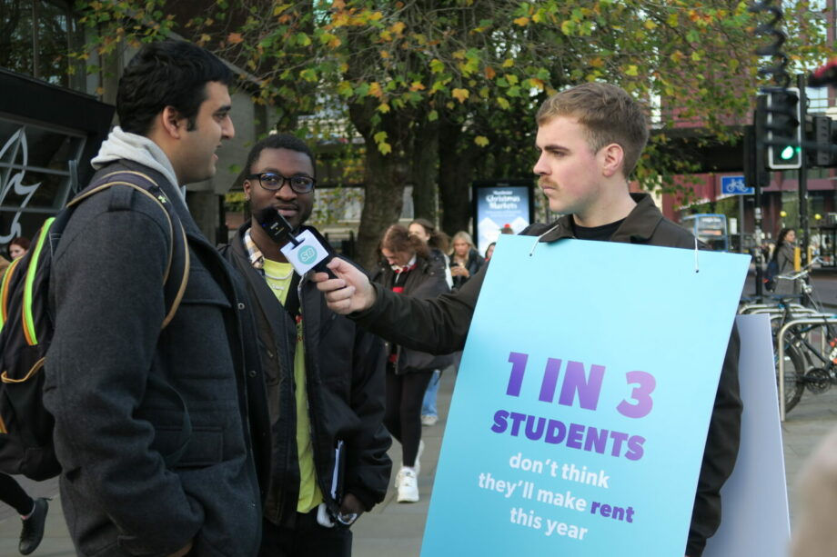 student beans worker wearing placard saying 1 in 3 students don't think they'll make rent this year, holding a mic interviewing students