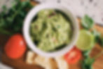 Avocado in guacamole form with lime and tomatoes