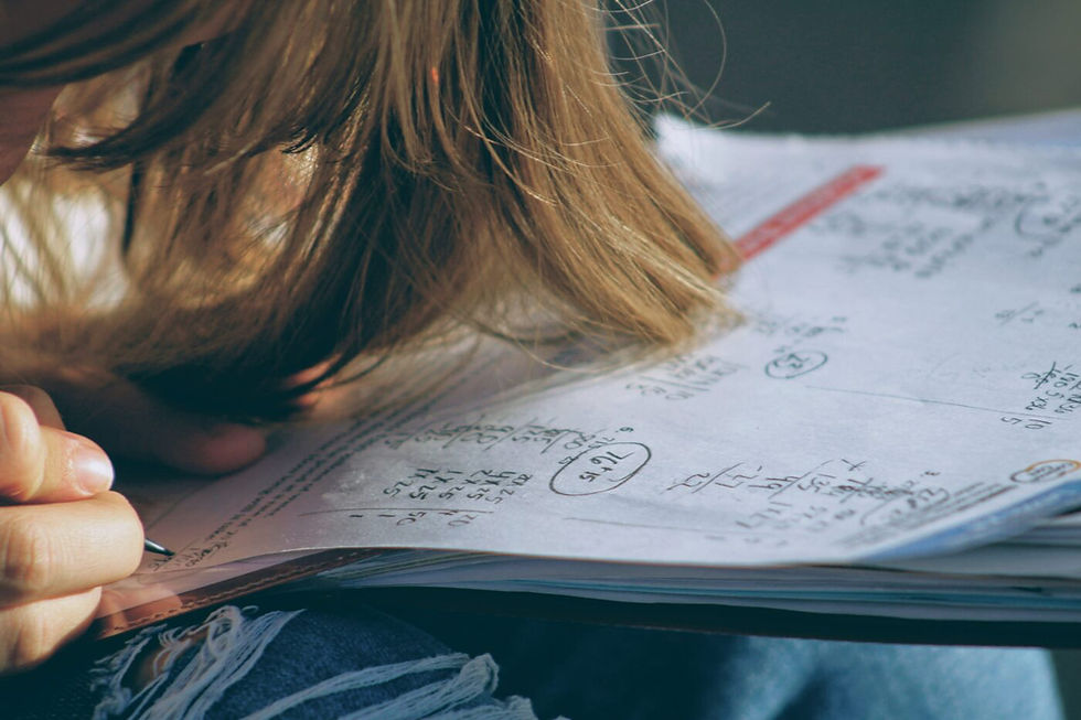 Person with long hair hanging over their book writing study notes in a book