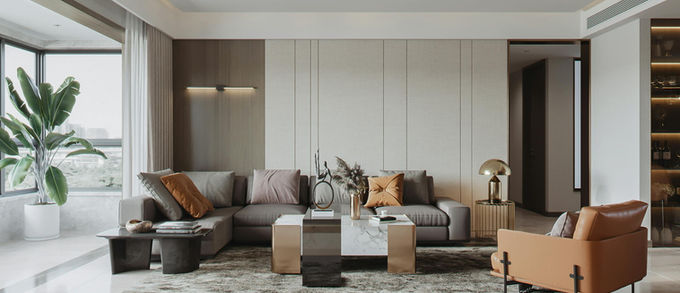 Salon moderne italien 2026 avec mur beige, groupe d’armoires blanc cassé, du sol au plafond, canapé gris avec méridienne et coussins terracotta, fauteuil en cuir terracotta, tapis graphique, table basse blanche avec détails en laiton, ambiance élégante et épurée.