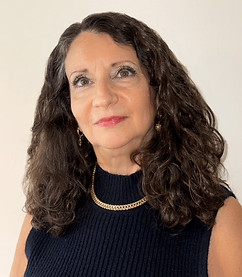 Portrait of Carol Michaels, a white woman with long curly brown hair wearing a ribbed, black top.