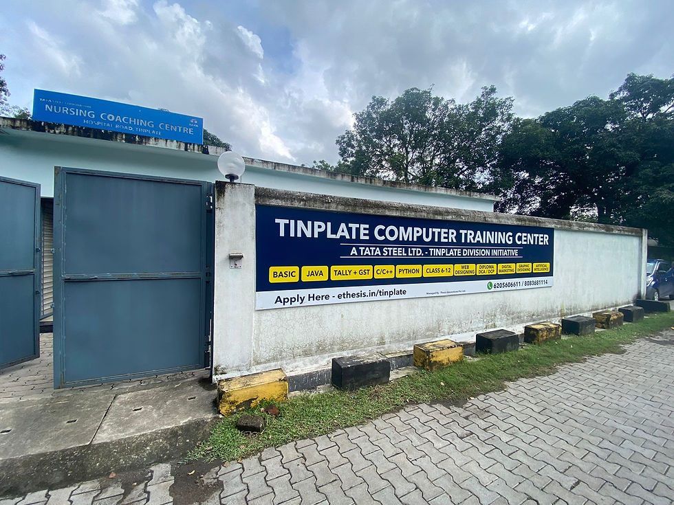 Sign for Tinplate Computer Training Center on a white wall with course details. Blue gate, cloudy sky, trees in background.