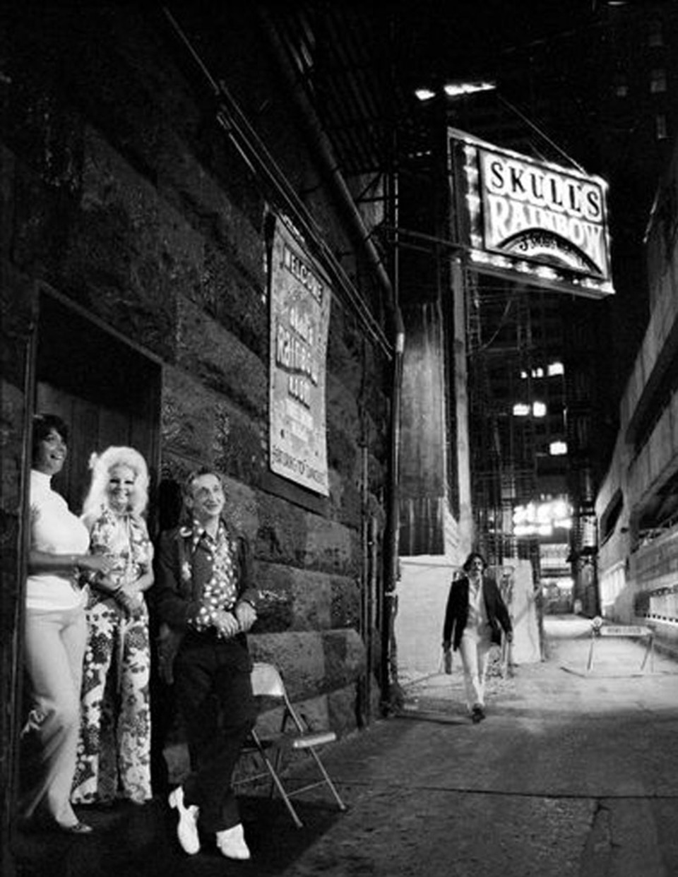 Vintage black-and-white photograph of the Skull's Rainbow Room neon sign in Printers Alley, Nashville, with patrons standing in the historic stone doorway